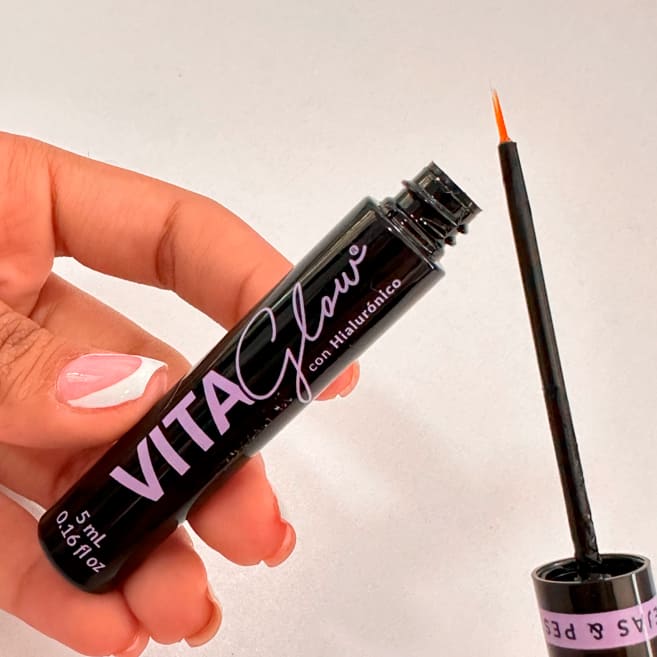 Frasco abierto con el aplicador de pincel fino en la mano – VitaGlow gel para el crecimiento de pestañas | Nova Oficial