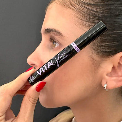 Mujer de perfil sosteniendo el frasco junto al rostro – VitaGlow gel para el crecimiento de pestañas | Nova Oficial