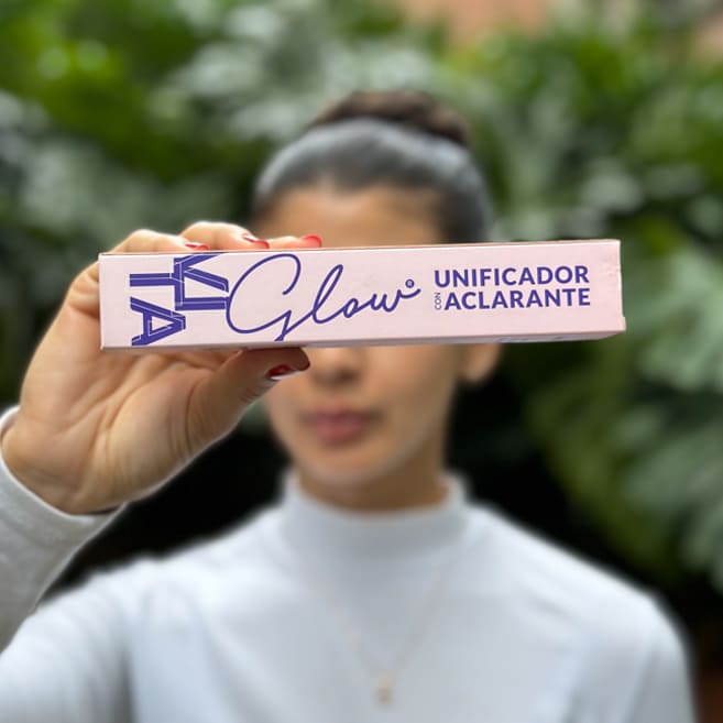 Mujer sosteniendo la caja del sérum unificador aclarante – VitaGlow sérum aclarante | Nova Oficial